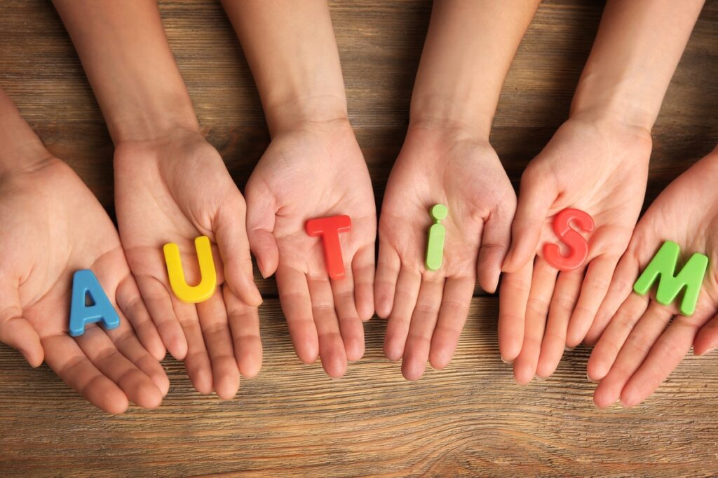 Letters making up the word autism on the palms of a few hands.