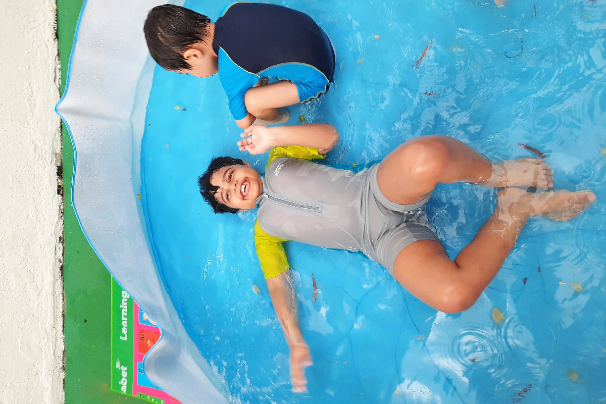 An exuberant boy splashing and playing in a kids' pool.