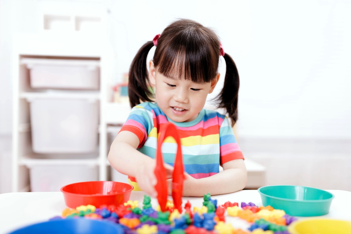 A young girl plays a colour sorting game to improve her fine motor skills.