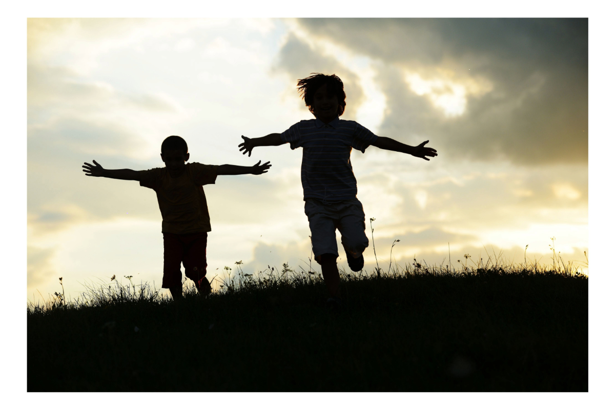 Silhouette of two active kids in the outdoors.