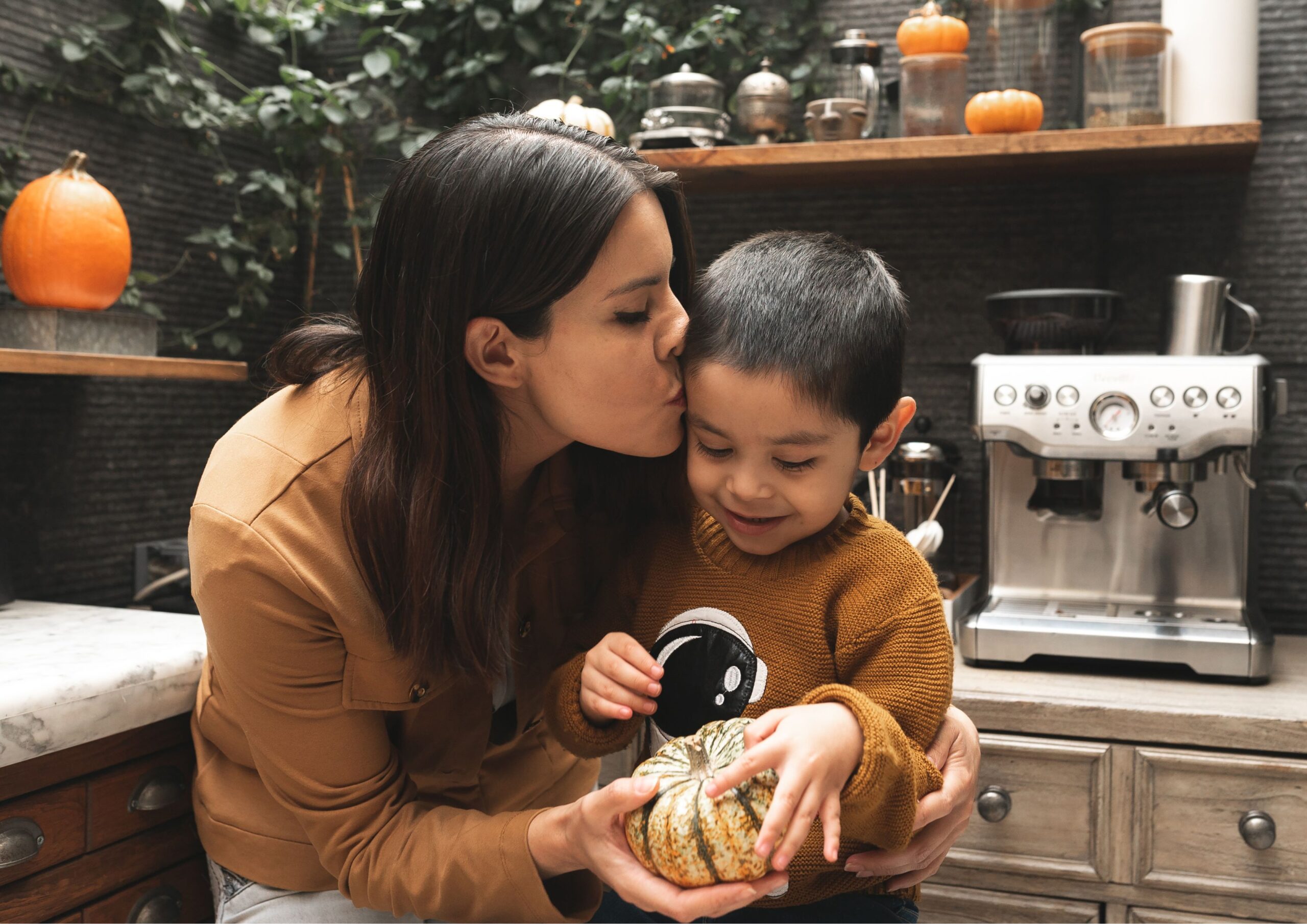 Autism in Malaysia: A mother kisses her child’s head in a kitchen, showing love and acceptance.