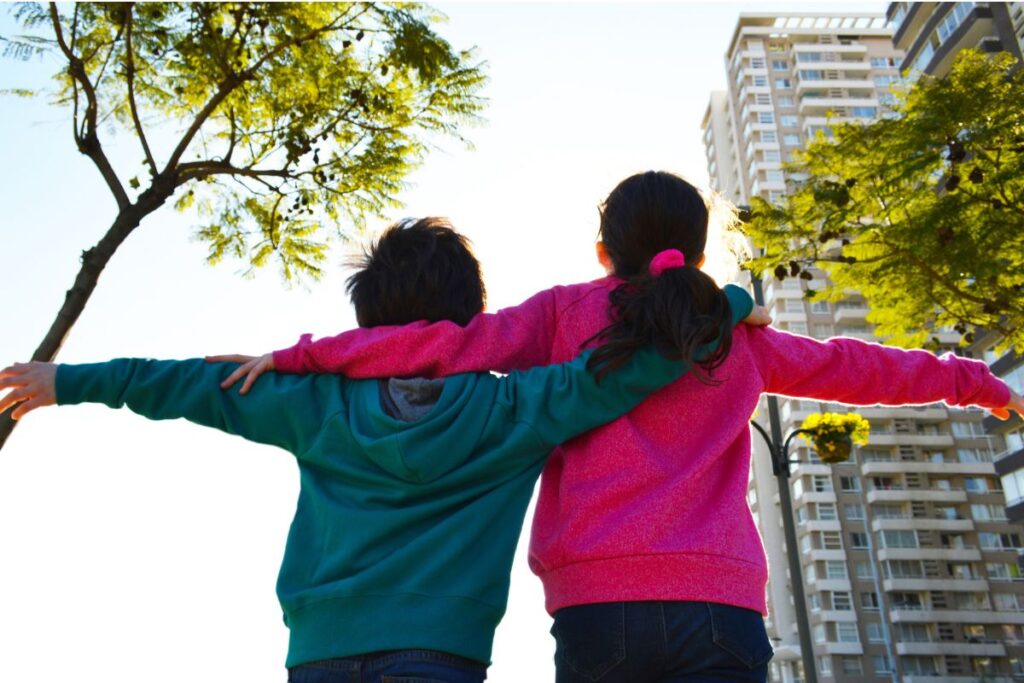 Two kids with arms around each other, showing love and support between siblings of children with special needs.